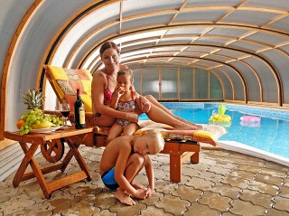 Famiglia felice sotto la copertura piscine Laguna NEO con la struttura in legno