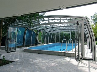 Retractable pool enclosure with open door by a house