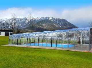 L’abri de piscine OMEGA en couleur argentée avec des montagnes en arrière-plan