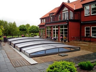 Retractable swimming pool enclosure Viva looks magnificent with red house in the background