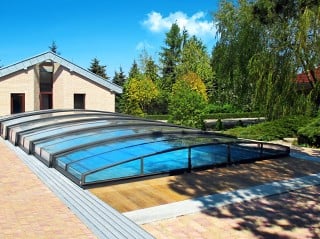 Pool enclosure Corona fits great into garden with modern house in the background