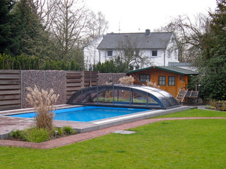 Perfect match of garden house and dark color of aluminium frames on pool enclosure Elegant
