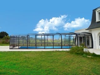 Open retractable pool enclosure with open door by a house