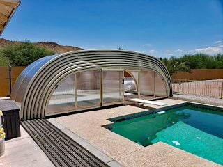 Pool with diving board covered by LAGUNA pool enclosure